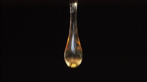 Macro shoot of thick liquid drop of oil or honey falling over black background