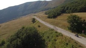 Aerial view of a man driving a motorbike on a mountain road. Drone video of motorcycle on a road winding through the countryside. Transport and travel concepts