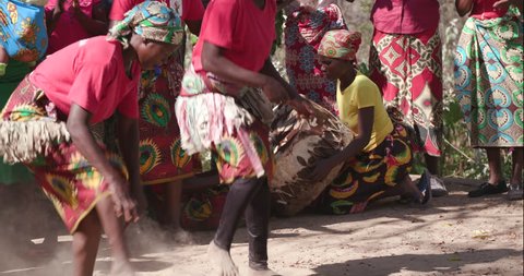 4K close-up view of two rural woman of the Shangaan tribe passing a stick around their legs doing a traditional dance at a social gathering, Mahenye Village, Zimbabwe