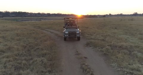 4K aerial zoom out view of a tourist on a 4x4 safari vehicle going on a game drive at sunset, Verney's Camp,Hwange National Park, Zimbabwe
