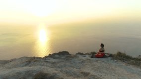 Beautiful view of woman doing yoga Baddha Konasana, Bound Angle Pose on the mountain with sea view at sunset.