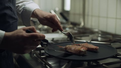 Professional restaurant chef cooking large shrimp wrapped in bacon on a skillet over a burner to cook. Close up shot on 8k helium RED camera.