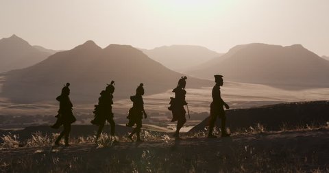 4K view of people from the Himba tribe in traditional dress, watching the sun setting on the mountains, Namib desert, Namibia