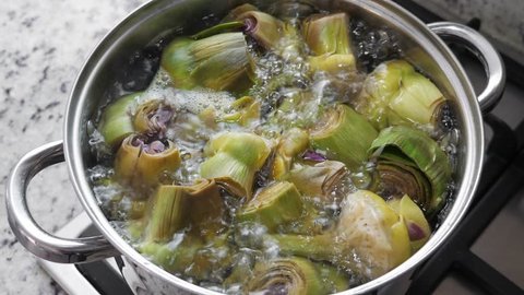 Boiling and cooking artichokes in saucepan, closeup