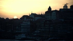 Timelapse video of large orange sun setting behind the Porto old town buildings silhouettes, Portugal