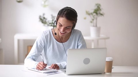Happy woman in headphones speaking by webcam at webinar training look at laptop make notes, girl student talking by video conference call, online teacher teaching consulting client e-coaching concept