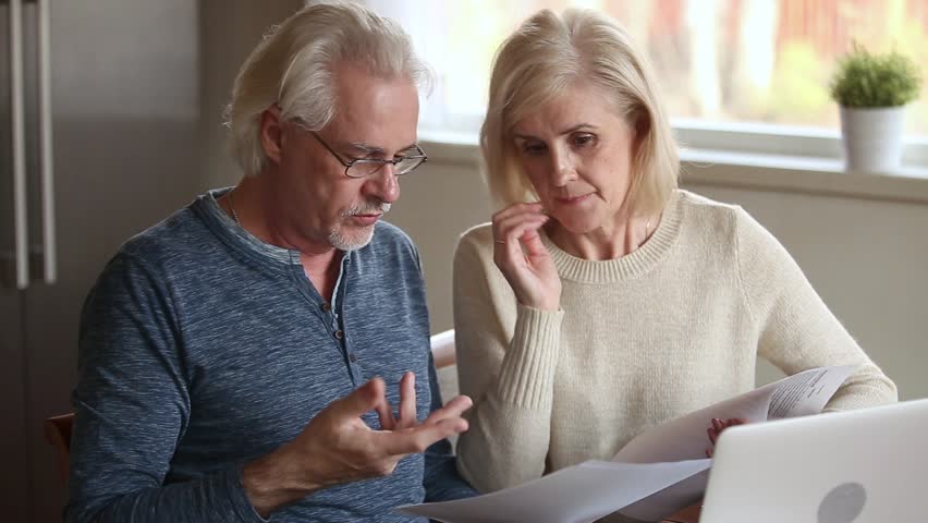 Serious senior mature couple talking disputing holding paper bills checking finances expenses, older middle aged family reading bank loan payments documents at home worried about debt money problems Royalty-Free Stock Footage #1024093961