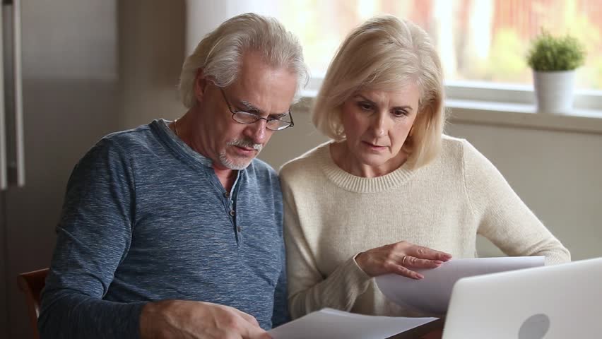 Serious senior mature couple talking disputing holding paper bills checking finances expenses, older middle aged family reading bank loan payments documents at home worried about debt money problems Royalty-Free Stock Footage #1024093961
