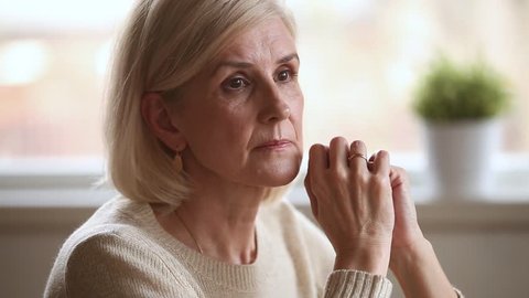 Sad thoughtful anxious mature senior woman feeling lonely worried concerned about problems, pensive depressed upset middle aged widow lady sitting alone grieving thinking of getting older loneliness