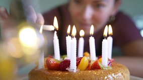 Woman lighting candles on fruity birthday cake 