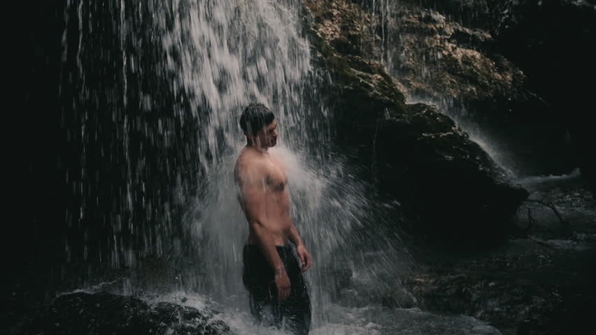 Young man in jeans standing under Niagara Waterfall on the river Cijevna in Podgorica, Montenegro
