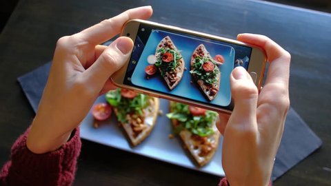 Female hands photographing appetizing food by smartphone in the restaurant. 4k. Delicious fresh waffles with spinach and cherry tomatoes ready in cafe.