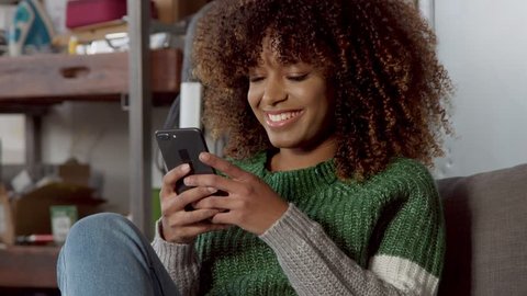 mixed race model with mobile phone smiling in cosy place