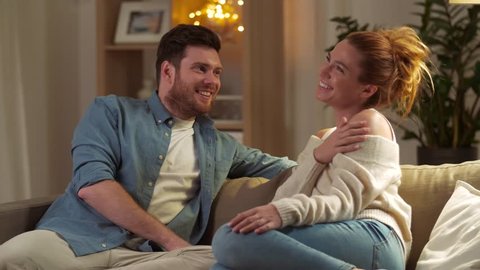 leisure and people concept - happy couple talking at home in evening