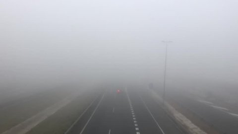 cars and trucks vehicle traffic on a highway on a dense fog day