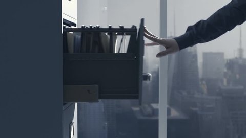 Office worker closing a filing cabinet's drawer and city view in the background