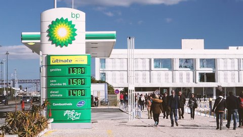 LISBON, PORTUGAL - CIRCA 2019: Cinematic colored slow motion people walk near BP British Petroleum gas station sunny day - digital prices for gas, petrol, gasoline gas and diesel