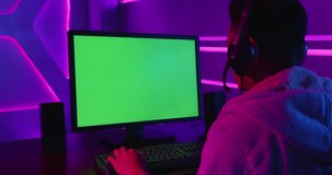 Young Asian Pro Gamer Playing in Online Video Game with green chroma key screen computer