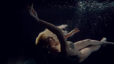 Sexy blonde woman swimming and posing underwater in a bikini. Beautiful mermaid like woman in underwater shooting.