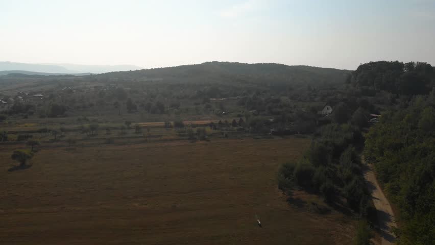 Aerial shot of a Romanian fields and forest. The sun is slowly setting.