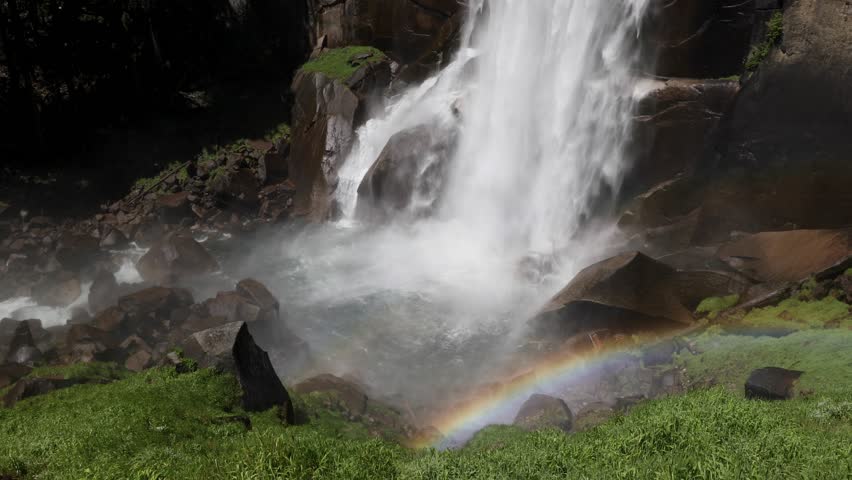 Seamlessly looping footage features a rainbow in the mists of plunging water splashing down at the base of Vernal Falls, a beautiful tall waterfall in Yosemite National Park, California.