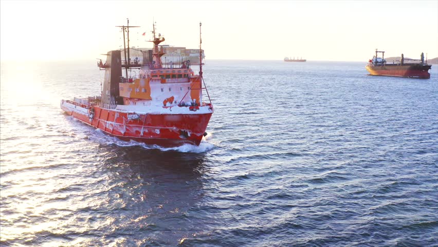 Aerial view of red fishing boat covered with frost sailing along the Eastern Bosphorus strait to Vladivostok. Sunny winter day. Russia