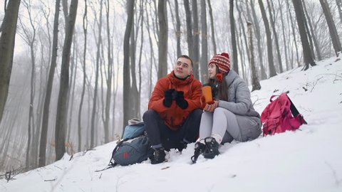Talking tired couple sitting in winter forest
