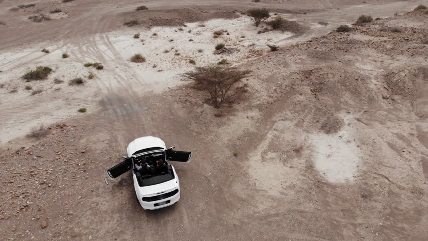 AERIAL. Couple inside the white car at the desert.