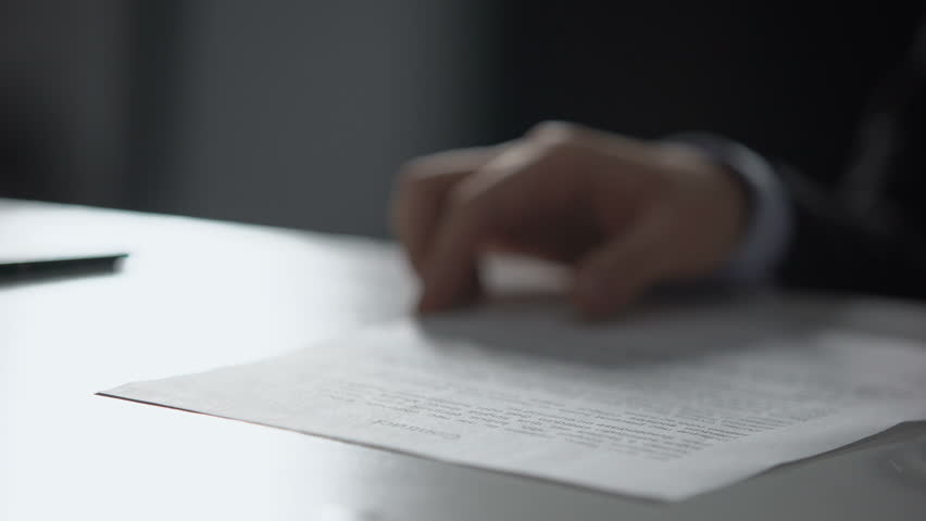 Business person smoking cigarette and throwing contract into trash, close-up
