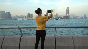 Young woman taking photo with tablet computer of Hong Kong skyline
