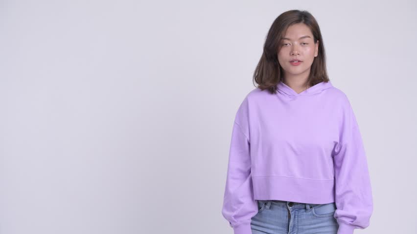 Young happy Asian woman snapping fingers and showing something