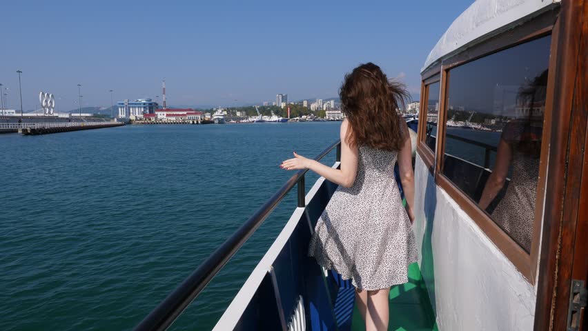 Cheerful woman run along old ship deck to bow, enjoy sunny weather and nice sea trip. Long hair and light dress fly on wind, slow motion shot, POV follow camera. City port seen ahead | Shutterstock HD Video #1024191575