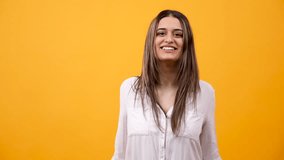 Happy excited woman clapping on yellow background in studio