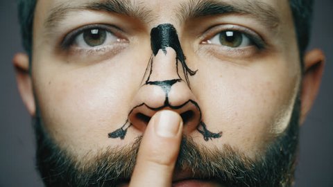 Funny twerk on the nose. Close-up portrait of a bearded guy with a painted girl on the nose, a man moves the tip of the nose with his finger forcing the figure to dance twerk
