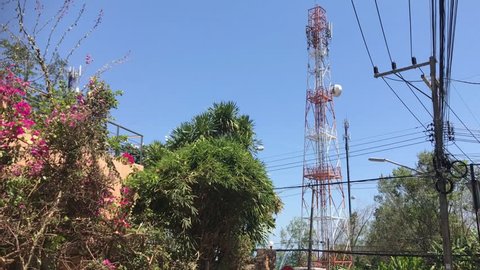 cellphone gsm antenna structure and communication and power lines against blue sky in summer environment, locked stabilized shot