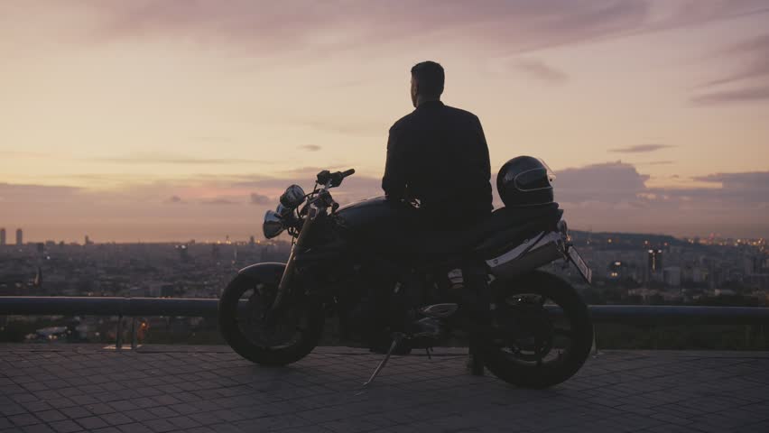 Silhouette of motorcyclist or traveler man enjoying new life and beautiful view of morning city in sunrise or sunset standing next to moto Feeling happiness and special moment of changes in loneliness | Shutterstock HD Video #1024209533