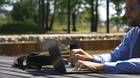 Young businessman watching movie on laptop at city park