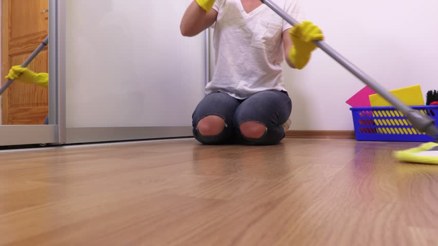 Woman sitting on floor and using mop