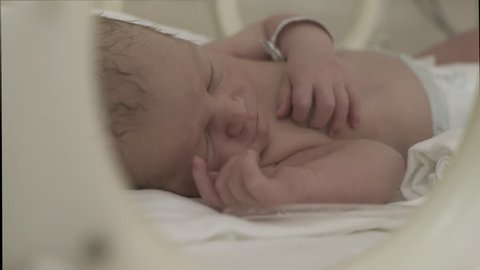 Portrait of cute newborn infant while sleeping  during treatment in incubator, face close up, beautiful little baby on intensive care unit at maternity ward in hospital. Dolly shot. indoors.