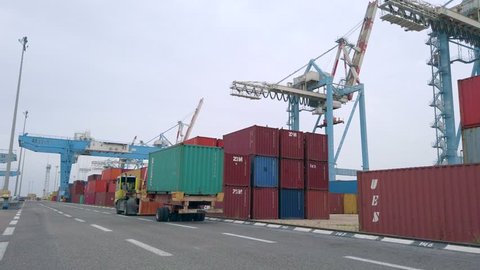 North District, Israel - February 2, 2019: Port work - Following a truck loaded with one container to a Transtainer that loads another container, at 60fps.