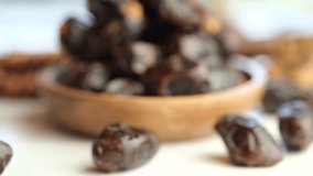 Dried date fruits in wooden bowl on table top. Selective focus. Tracking shot.