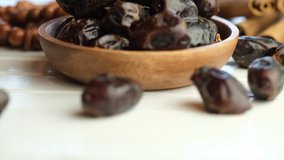 Dried date fruits in wooden bowl on table top. Selective focus. Tilt up shot.
