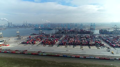 Aerial flight over Rotterdam harbour in Netherlands industrial landscape storage containers clear blue water 4k