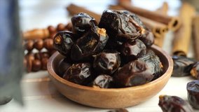 Dried date fruits in wooden bowl on table top. Selective focus. Panning to the left.