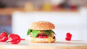 Hamburger with bun and red pepper on a wooden table. Closeup view 
