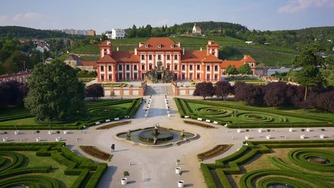 Prague, Czech Republic - 5.07.2017: Beautiful aerial drone view of luxury summer residence Troja Chateau (Troja Palace) with walking people in gorgeous French garden and vineyards on background