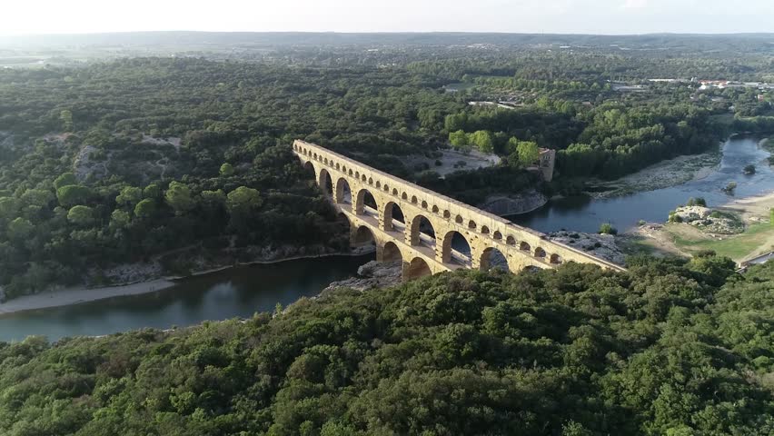 Aerial bird view footage Pont du Gard is ancient Roman aqueduct that crosses Gardon River near towns of Remoulins Avignon and Nimes in southern France it is on UNESCO's list of World Heritage Sites 4k Royalty-Free Stock Footage #1024272791