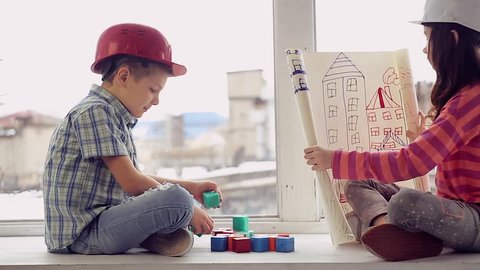 boy and girl playing builders on the background of an old factory