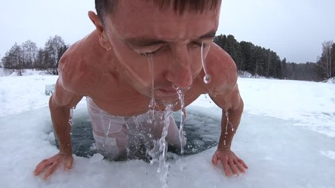Young man haves recreational winter swim in the ice hole