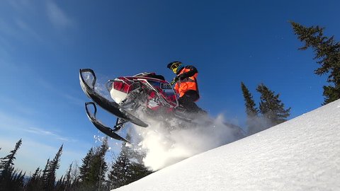 fantastic snowmobile jump. boondocking, blue sky. snowmobile with splashes of snow and whirlwinds. bottom view. the camera in the snow. 3D snow dust.  stock video footage. Slow motion